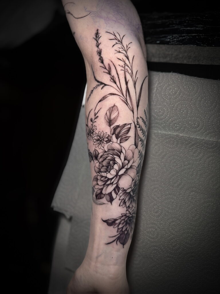 Fine botanical stems and layered flowers on a forearm