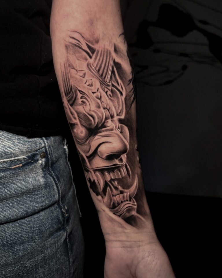 Shaded mask tattoo with flowing forms on a forearm